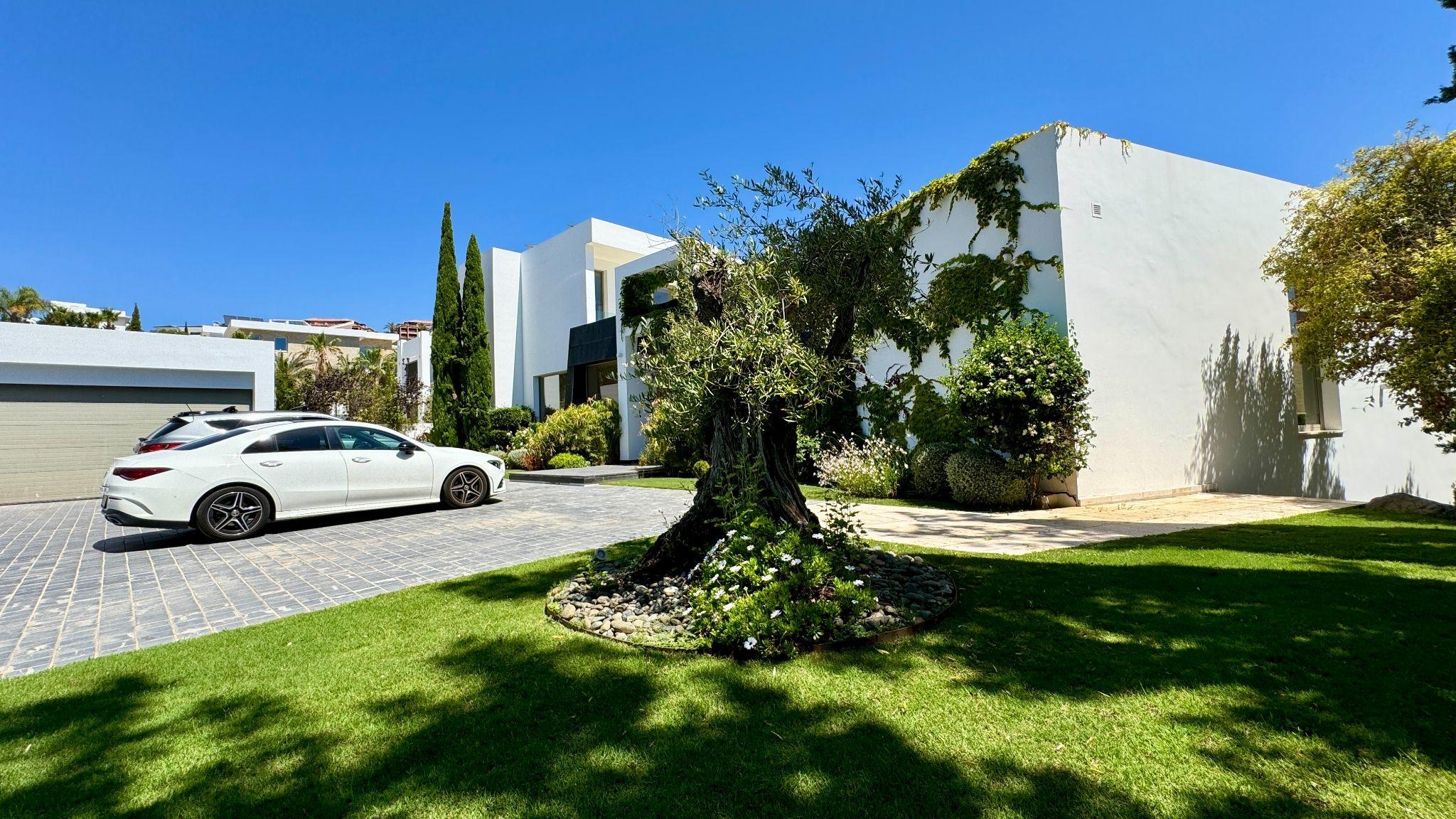 Modern white villa with landscaped garden and luxury car