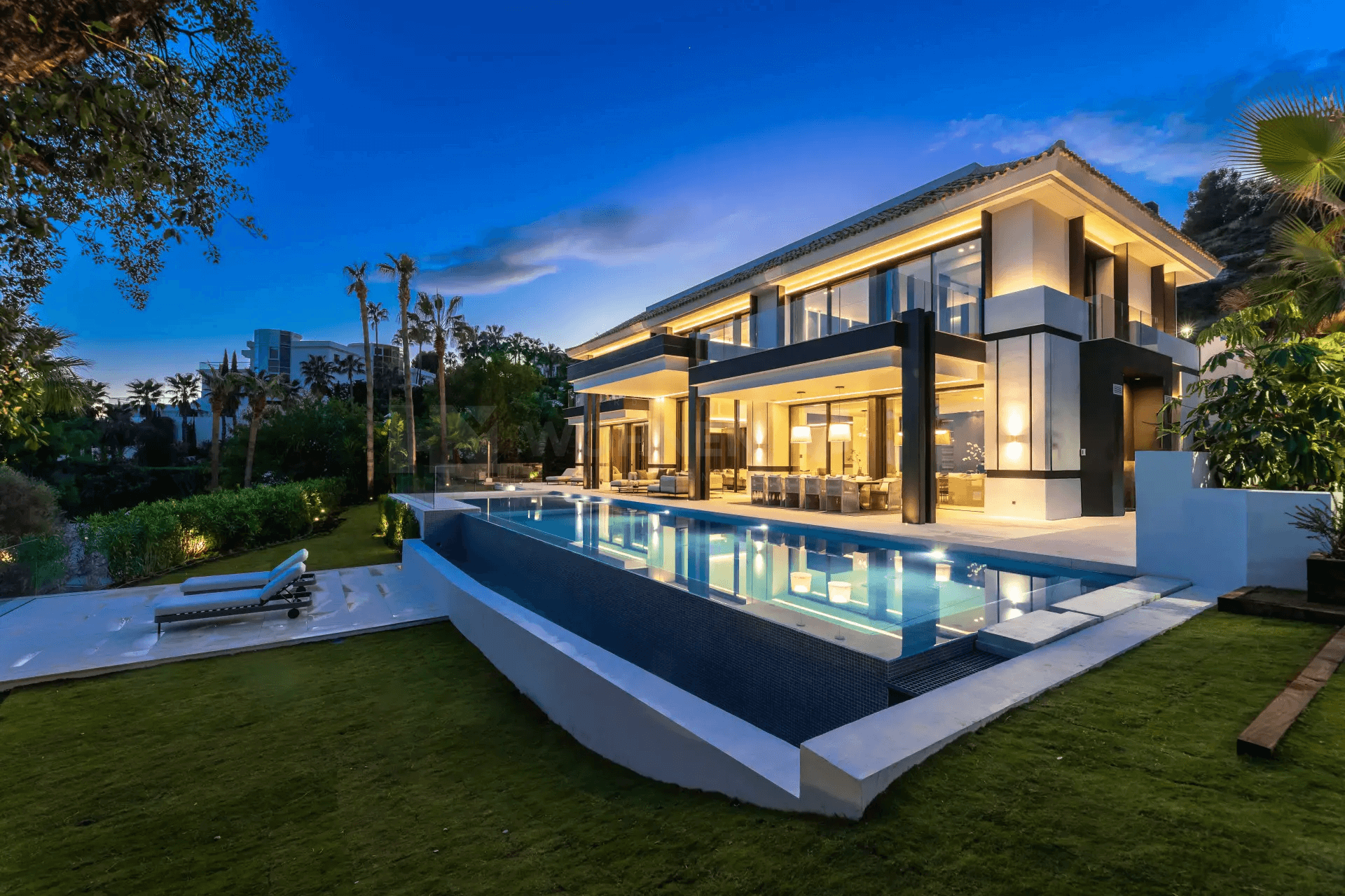 Contemporary villa at twilight with illuminated pool