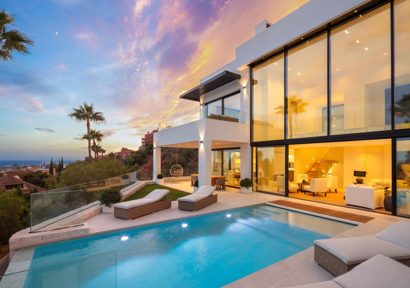 Modern villa at sunset with pool and palm trees in Marbella